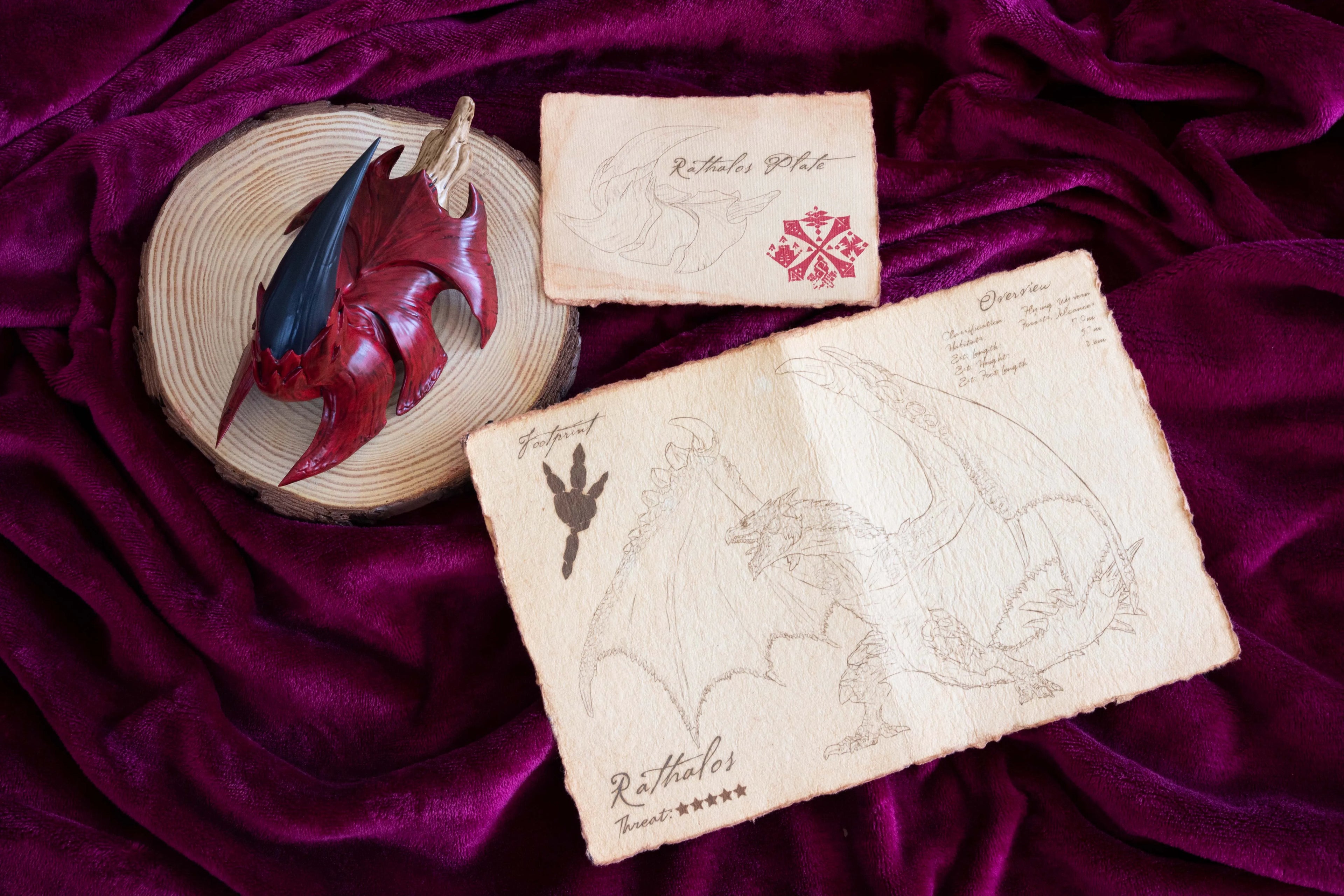 Rathalos Plate replica and parchment documents on red cloth background
